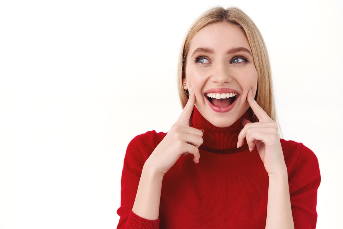 Joven sonriendo ampliamente, mostrando dientes bellamente alineados después de una remodelación de la sonrisa.