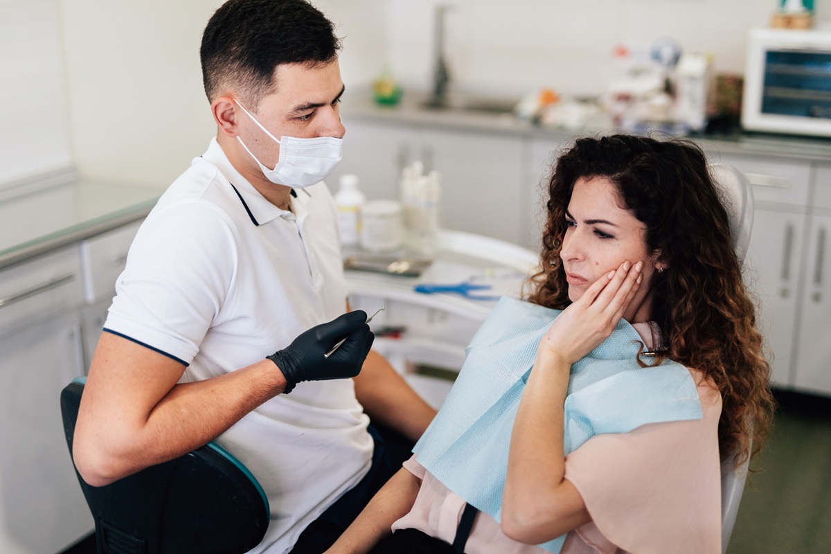 Mujer con dolor de muelas consultando a un dentista durante una visita dental de emergencia.
