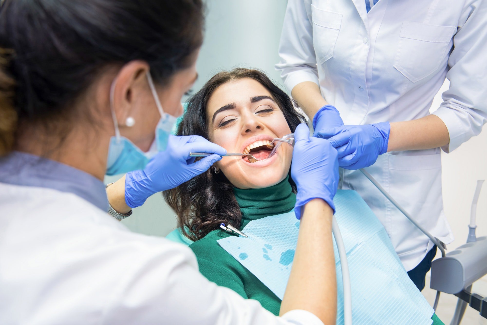 Dental Emergencies in Houston - InStyle Dental Group Patient receiving urgent dental treatment in a sterilized clinic by a dentist and assistant.