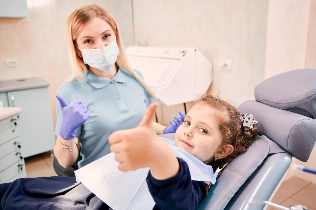Dentista y niño sonriendo durante una visita de limpieza dental que promueve la higiene bucal para los niños.