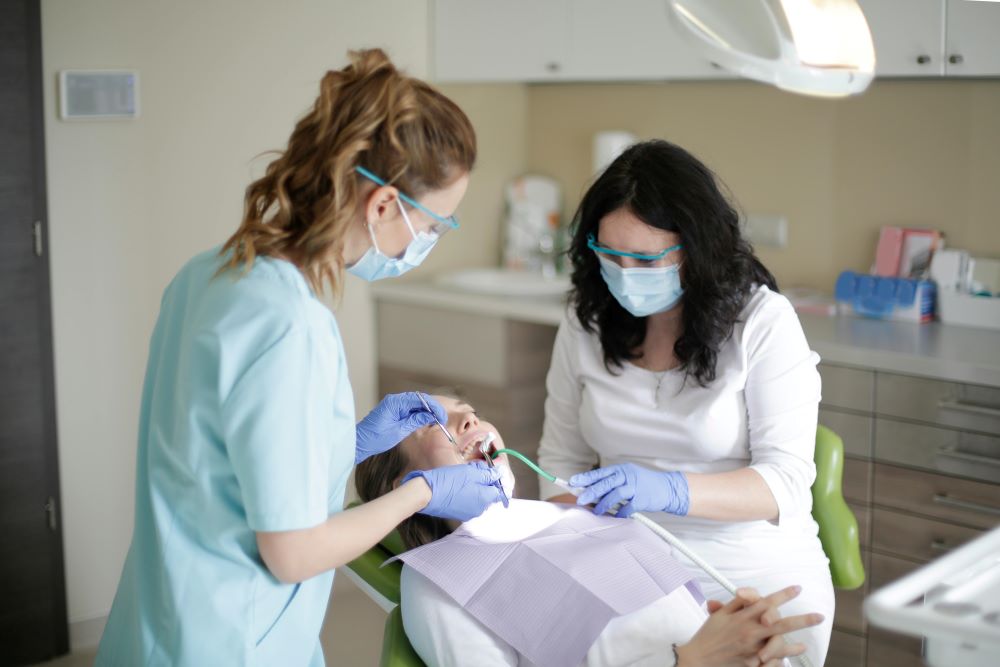 Dentista y asistente realizando una limpieza dental profesional en un entorno de clínica higiénica.