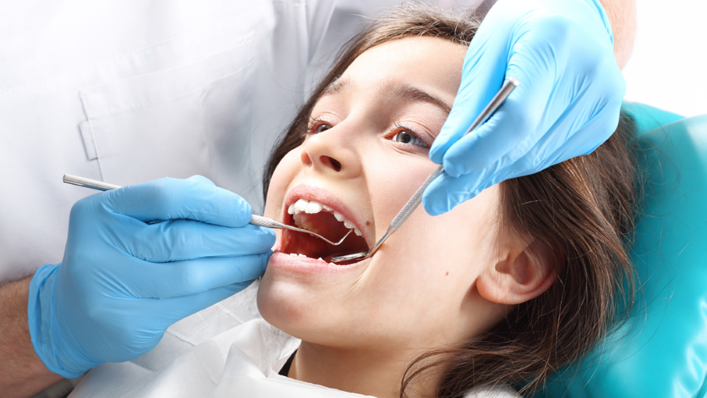 Niño recibiendo una limpieza dental de rutina para mantener los dientes sanos y prevenir las caries.